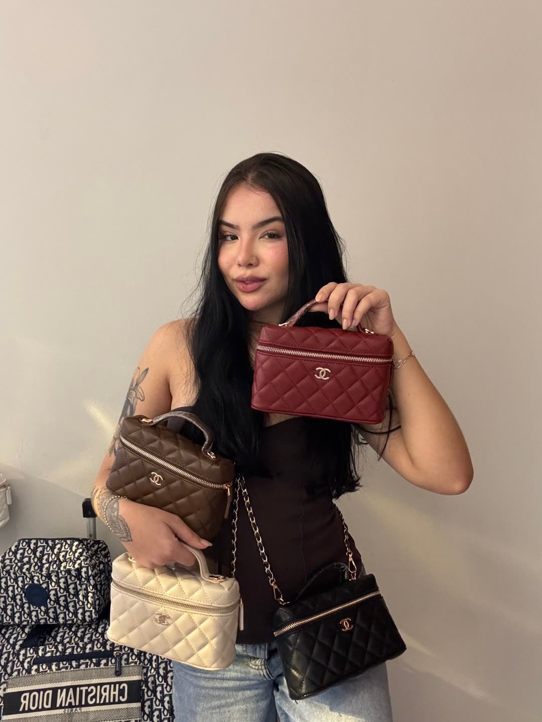 Modelo segurando quatro bolsas matelassê nas cores vinho, café, off-white e preta